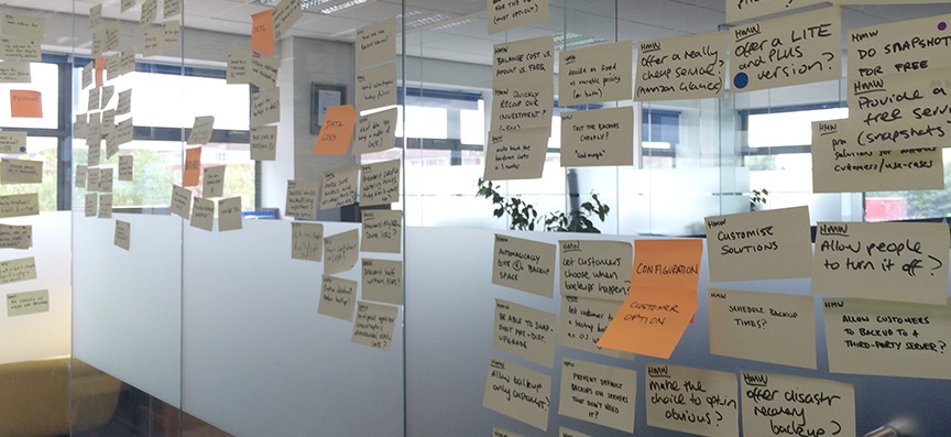 A glass wall covered in sticky notes from the design sprint