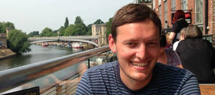 Steve Urmston, smiling, at a riverside table